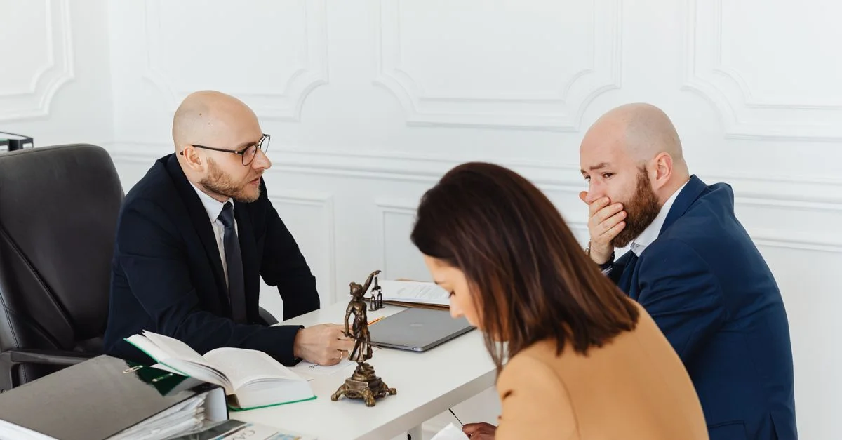 Une consultation juridique sérieuse dans un environnement de bureau professionnel impliquant trois adultes.